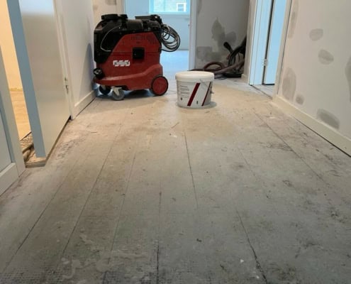 Gang under renovering med støvet gulv.