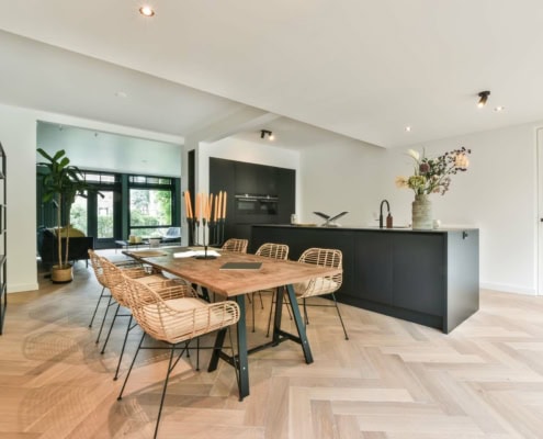 Lys stue med køkken i sort. Træ spisebord og stole.